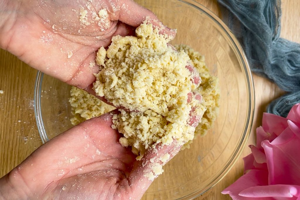 hands holding the crumble topping to show the breadcrumb stage.