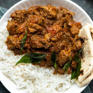 a plate of slow cooker beef madras served with rice and naan bread.