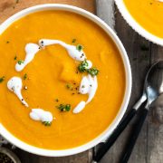 slow cooker pumpkin soup in a bowl topped with a swirl of coconut milk.