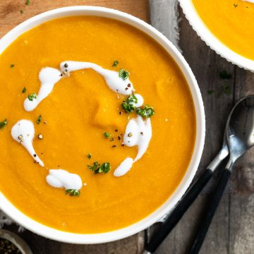 slow cooker pumpkin soup in a bowl topped with a swirl of coconut milk.