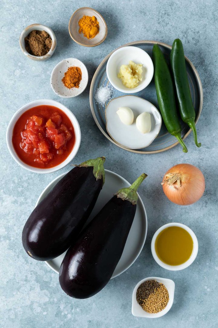 ingredients needed to make aubergine curry measured and placed on individual plates and bowls.