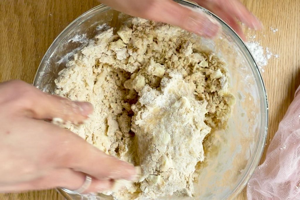 Using hands to bring the cookie dough together once the white chocolate has been added.