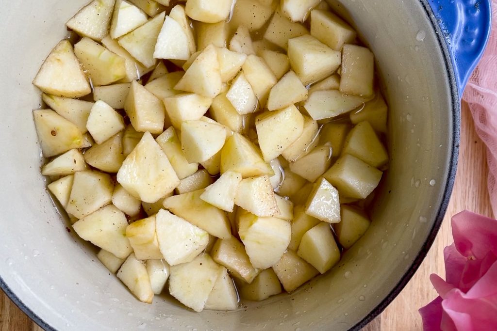 The chopped apples in a saucepan with water and sugar.