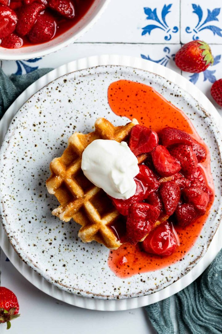 a plate with waffles and strawberry compote served with yogurt.