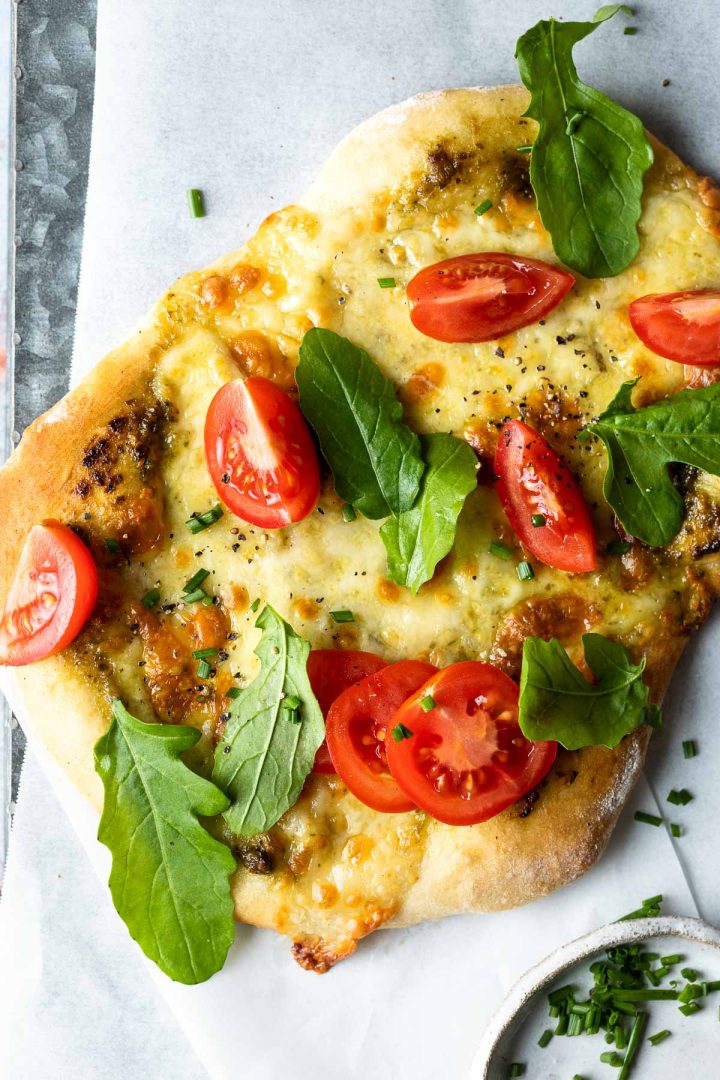pesto and cheese pizza topped with fresh rocket and cherry tomatoes.