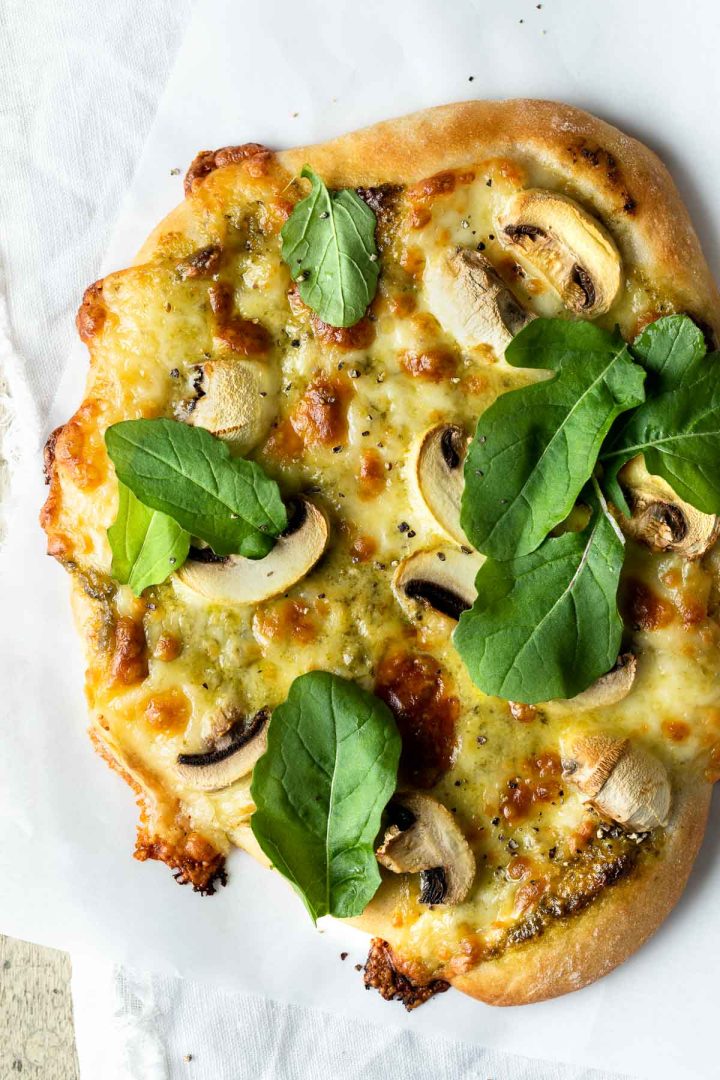 mushroom and pesto pizza topped with fresh rocket leaves.