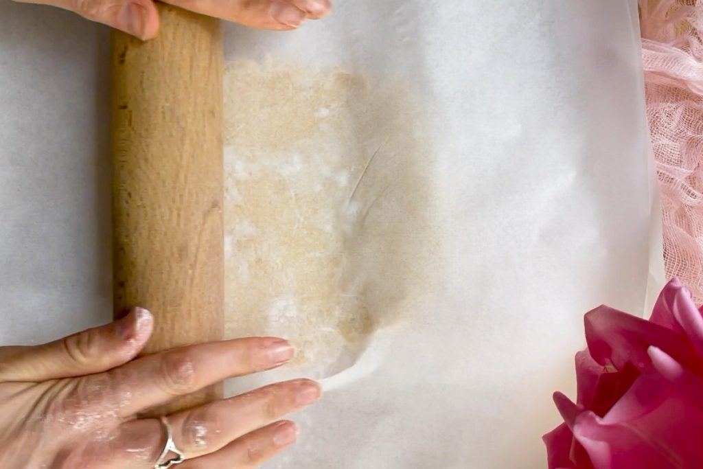 Rolling out the pastry between two sheets of baking paper.