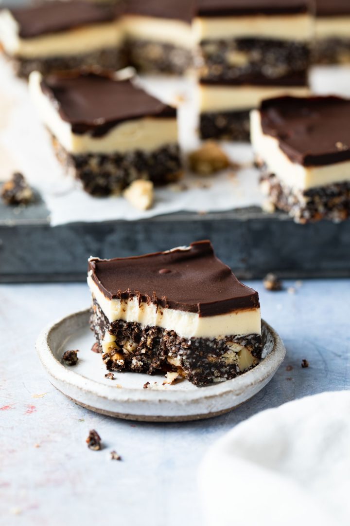 A Nanaimo bar on a plate with a portion eaten from it.