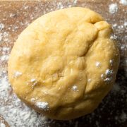 A ball of chilled shortcrust pastry on a floured board.