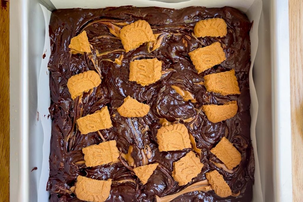 Broken Biscoff cookies placed on top of the brownies.