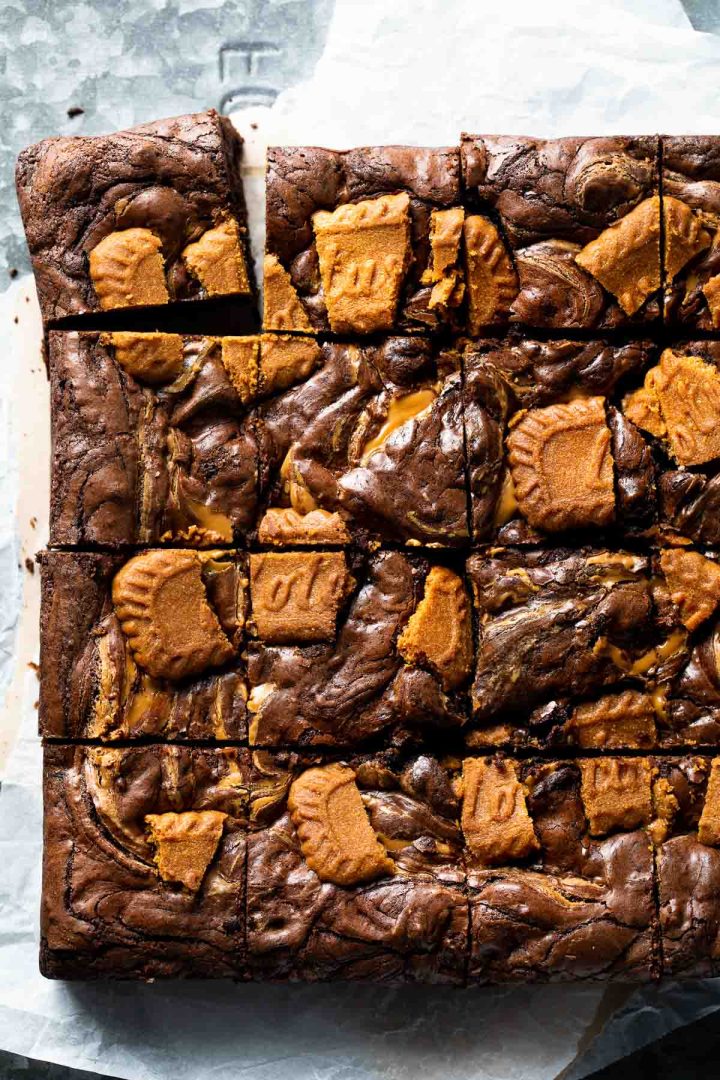 Close up of freshly baked brownies cut in to squares, showing the swirls of cookie butter and Lotus biscuits.