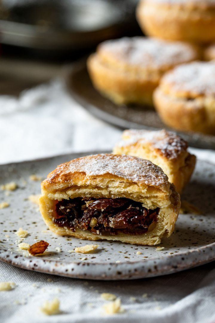 Cut fruit mince pie on a plate to show the flaky pastry and juicy fruit mince filling.