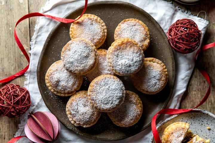 Shortcrust mince pies on a plate dusted with icing sugar.
