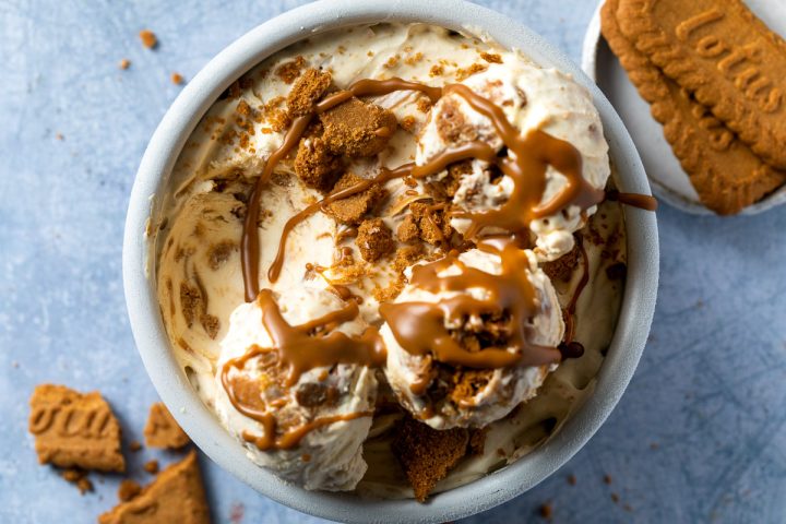 Biscoff ice cream in a round tub drizzled with Biscoff cookie butter.