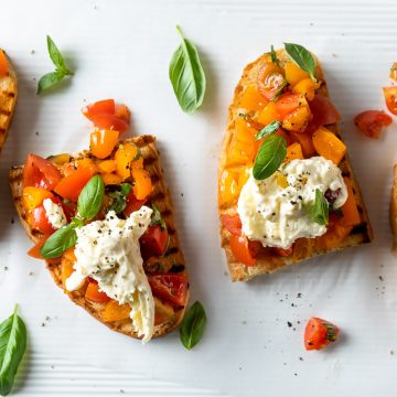 Slices of bruschetta with burrata, fresh tomatoes and basil.