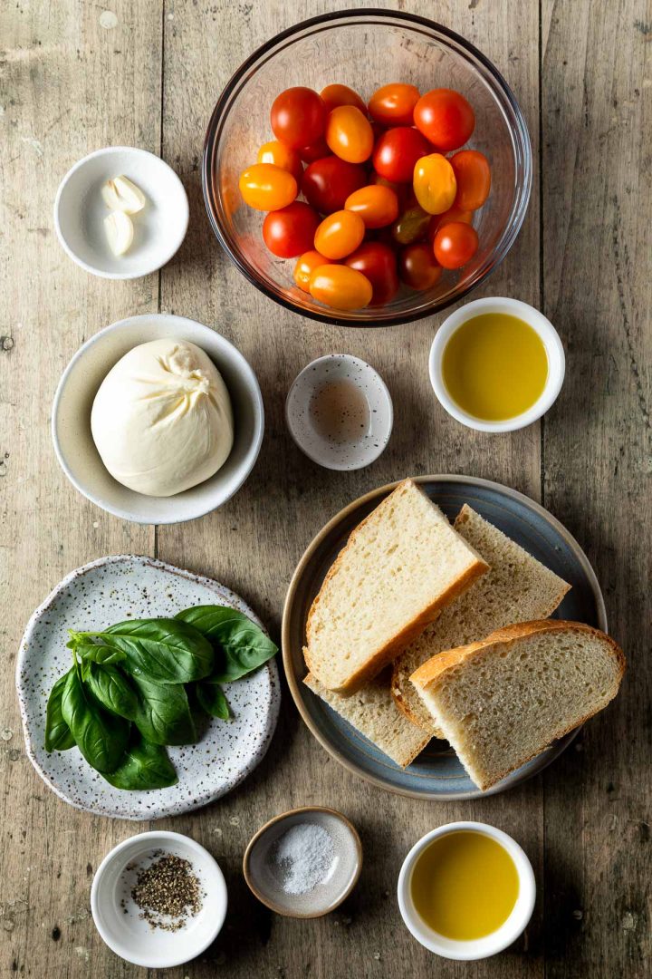 Recipe ingredients for burrata tomato bruschetta measured out into individual bowls.