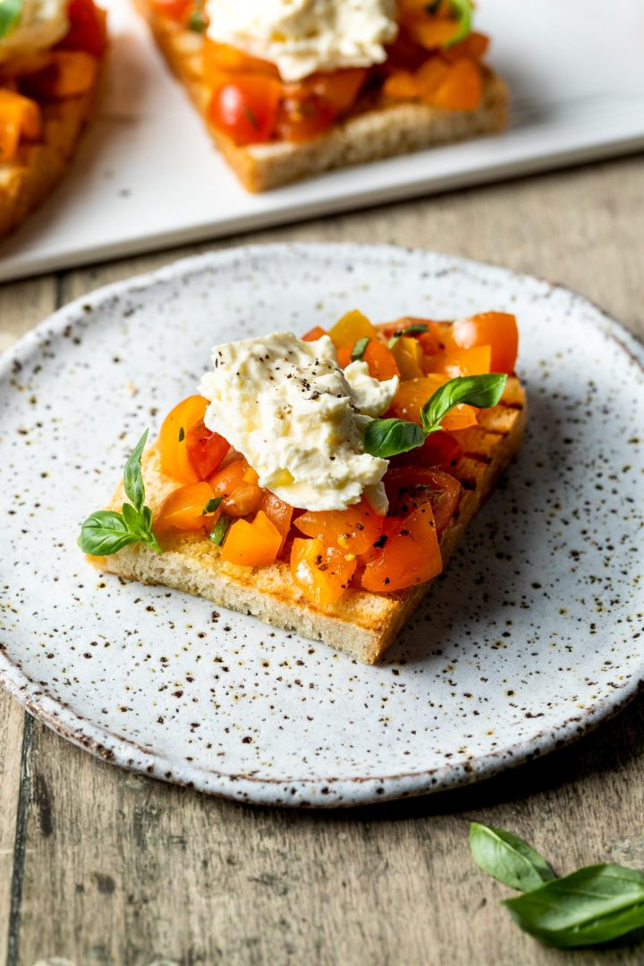 A bruschetta with tomatoes and burrata on a plate.