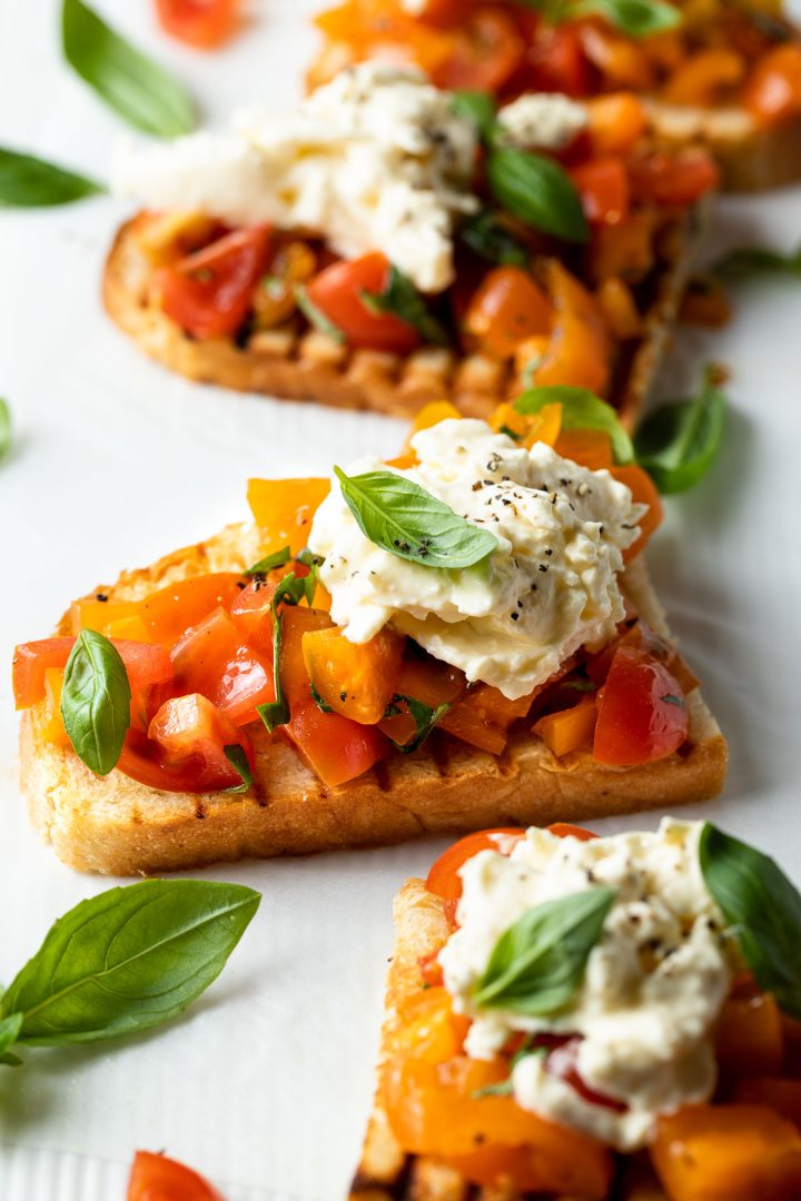 Side view of a bruschetta topped with burrata cheese.