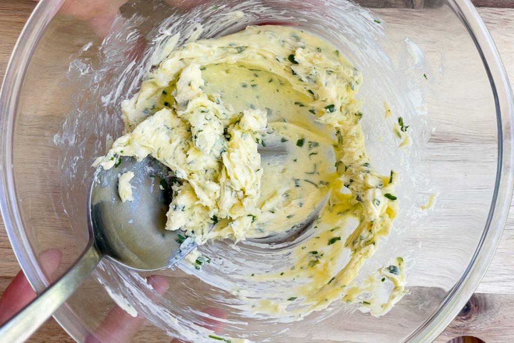Butter mixed with garlic, parsley and chives in a bowl.
