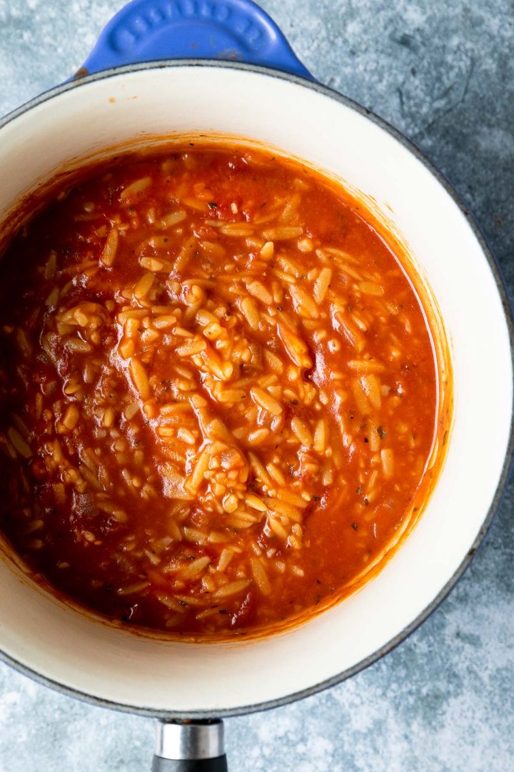 The cooked orzo in tomato sauce in a blue saucepan.