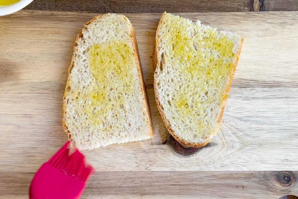 Brushing the sliced bread with olive oil.