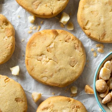 Close up of a baked white chocolate and macadamia cookie on white background.