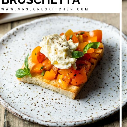 A slice of burrata bruschetta with tomato and basil on a plate with text overlay to create a pin for Pinterest.