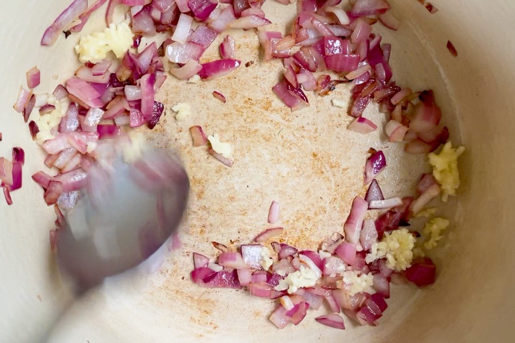Softened red onion in a pan.