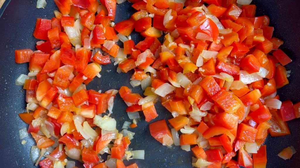 Cooked capsicum (pepper) and onion in a frying pan.
