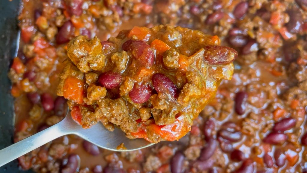 A spoon holding up a portion of slow cooker chili.