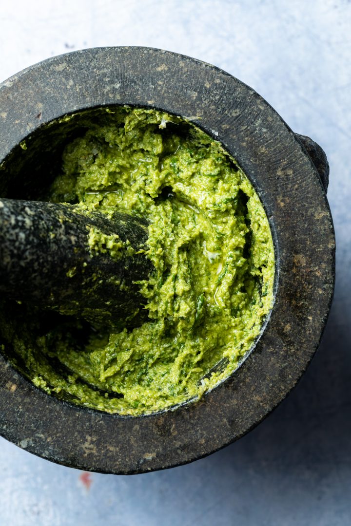The finished basil pesto in a pestle and mortar.