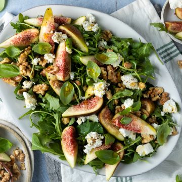 A white serving plate of fig and goats cheese salad.