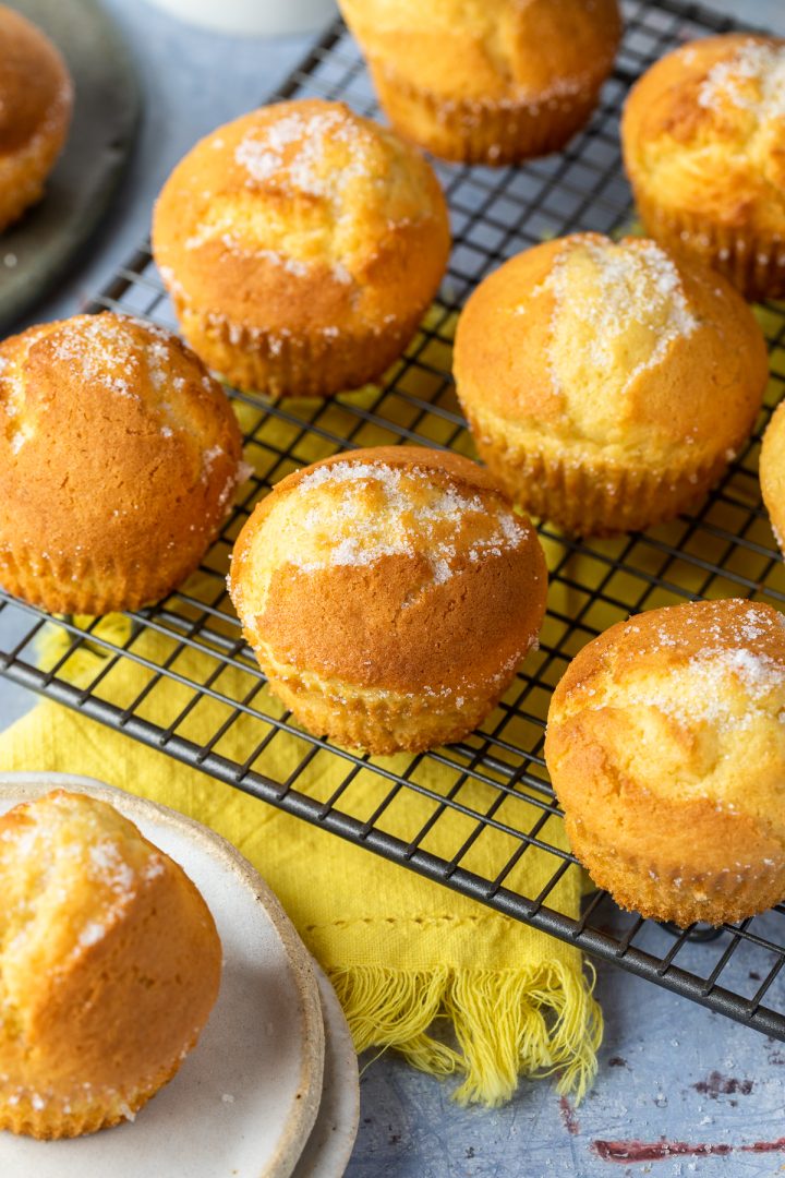 9 Spanish cupcakes on wire cooling rack, with one on a plate. A yellow napkin underneath.