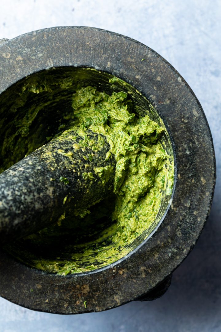 Pesto in pestle and mortar after basil has been added.