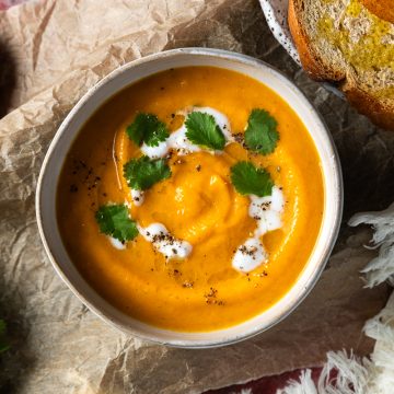 A bowl of carrot lentil soup served with toasted bread.