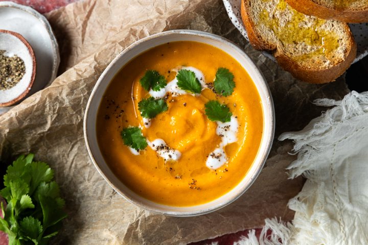 A bowl of carrot lentil soup served with toasted bread.