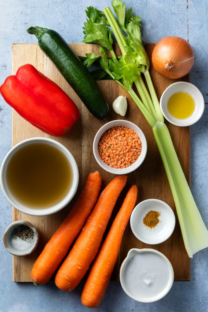 The ingredients needed to make the soup recipe measured out and placed on a wooden board.