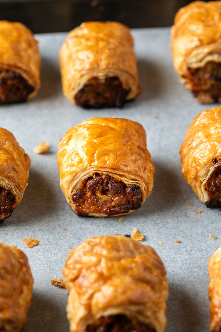 Freshly baked sausage rolls on a baking tray.