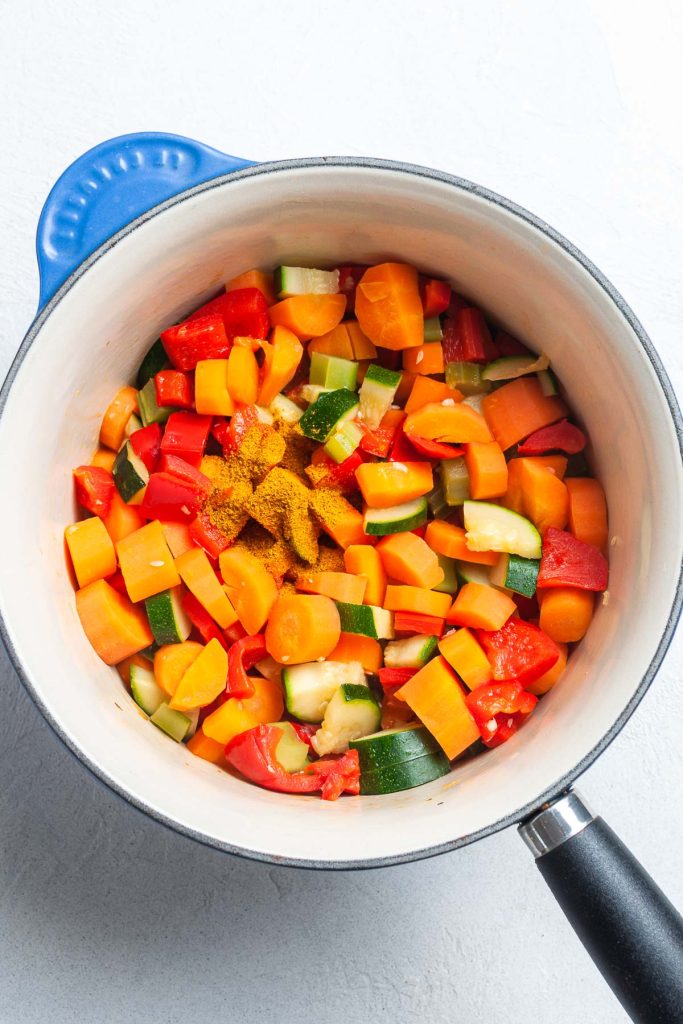 The softened vegetables in the saucepan with curry powder added.
