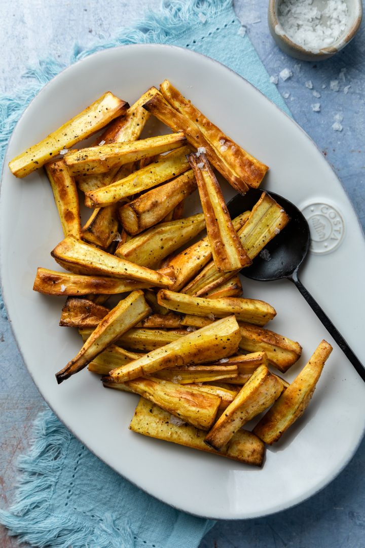 Roasted parsnips on a white serving plate.