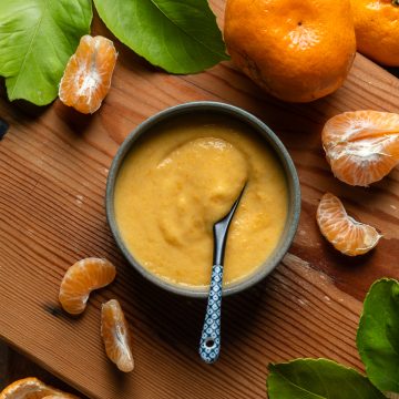 A blue dish of mandarin curd with a spoon ready to serve.