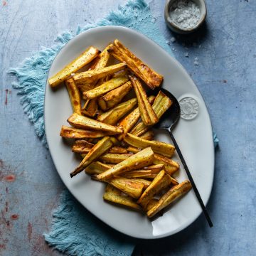Roast parsnips on a white serving dish.