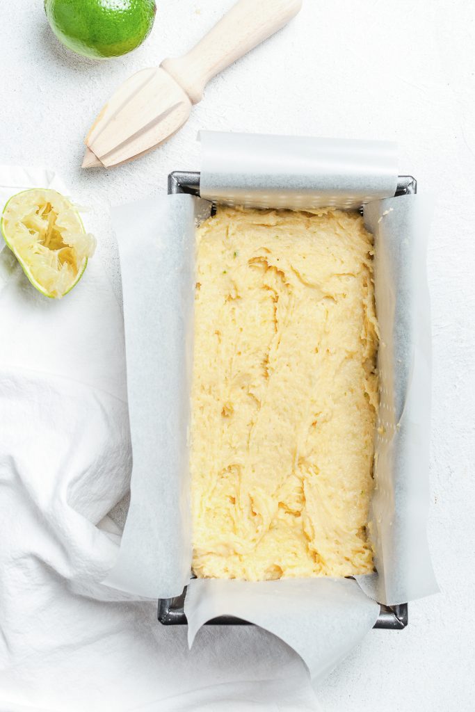 The cake batter spooned into a lined loaf tin.