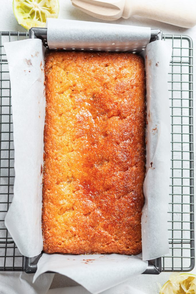 The lime drizzle poured over the baked lime cake in the tin.