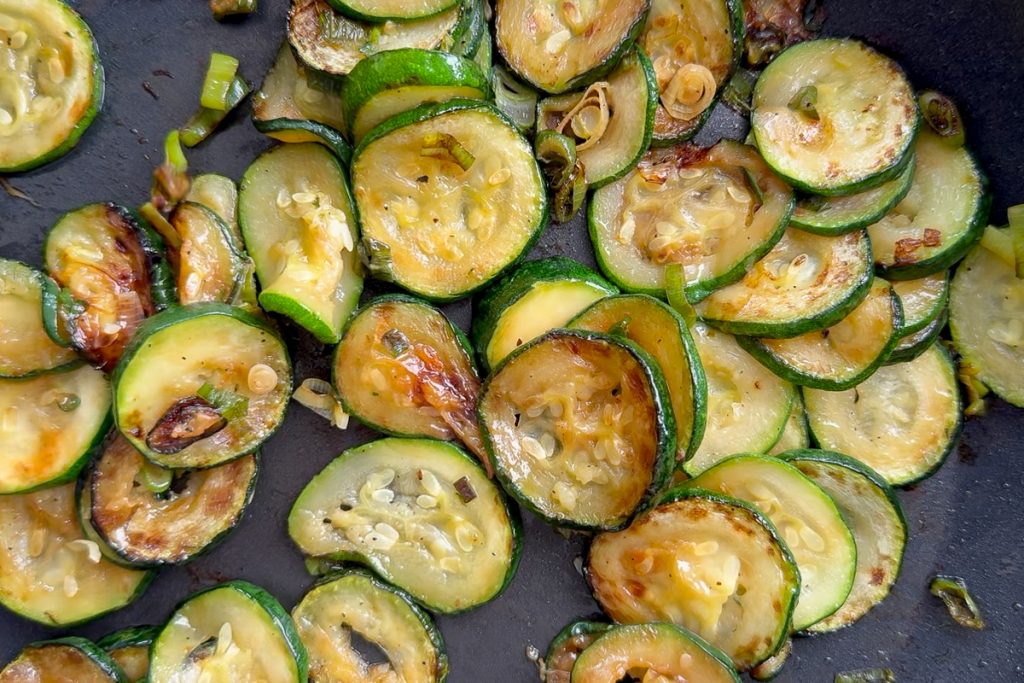 The golden fried courgettes in a frying pan.