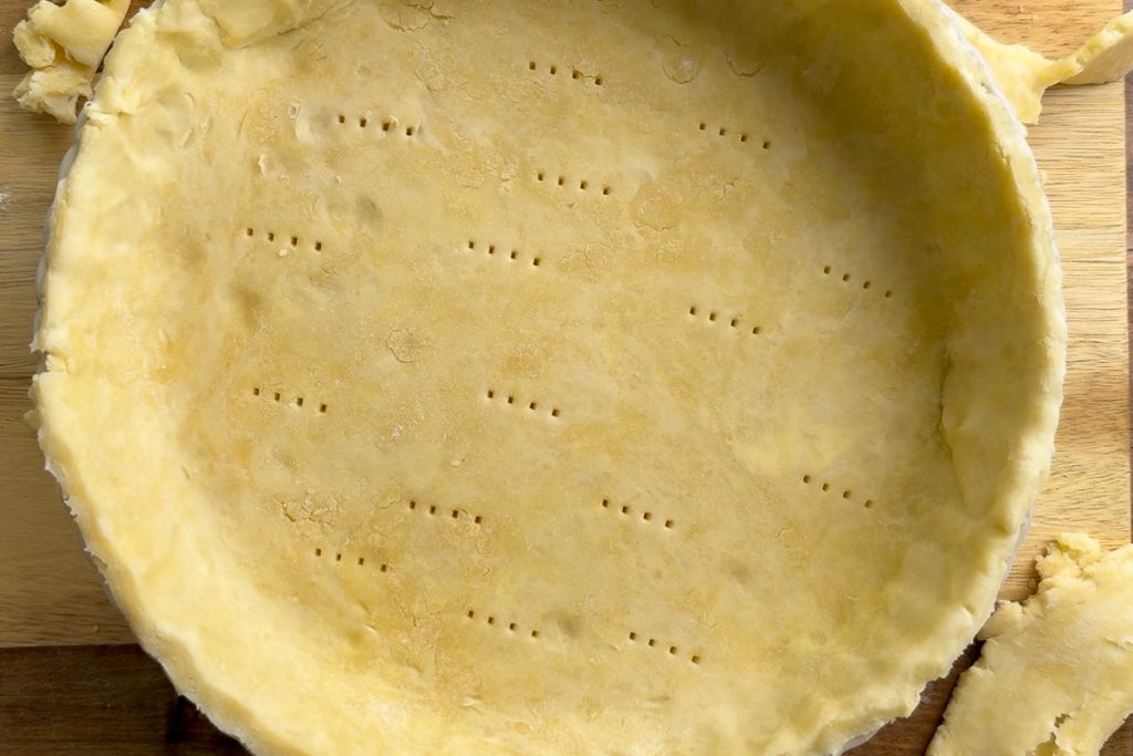 The rolled pastry lining the quiche tin.