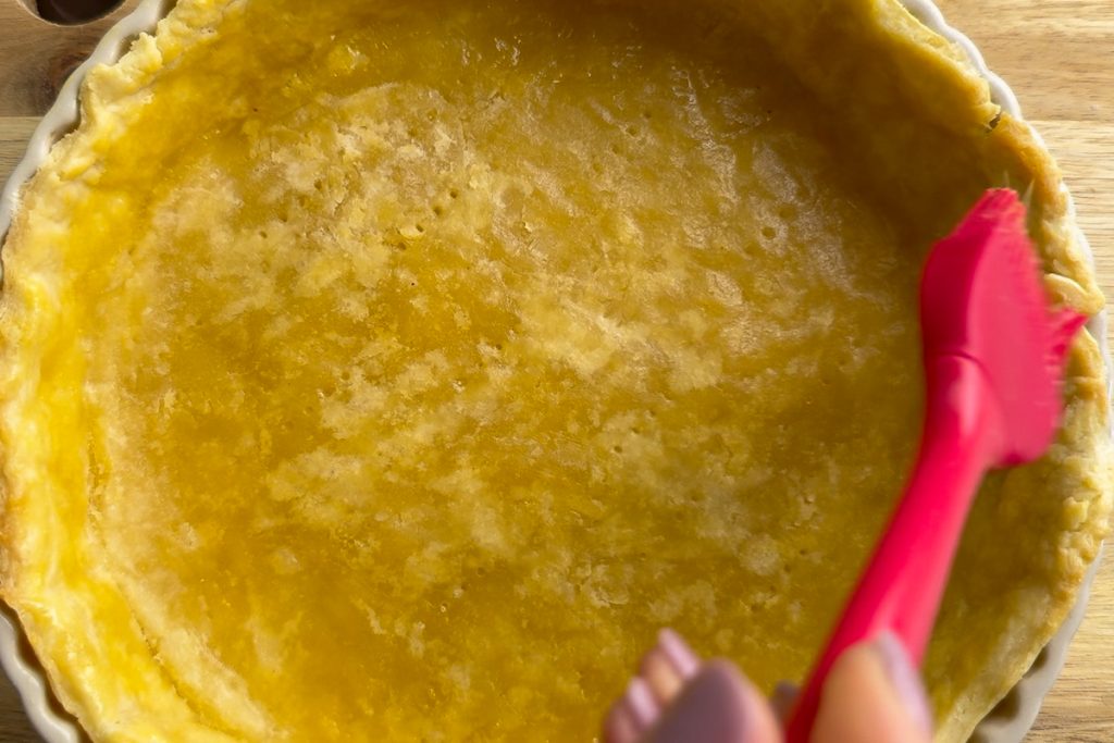 Brushing the pastry with an egg wash.