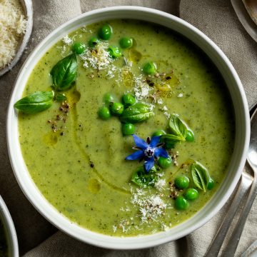 A bowl of courgette soup topped with basil and grated parmesan.