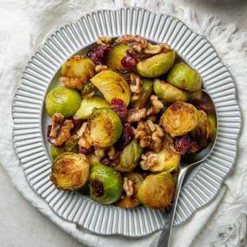 A serving plate of Brussels sprouts with cranberries and walnuts.