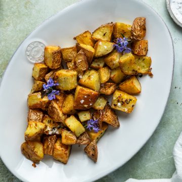A plate of parmentier potatoes decorated with fresh rosemary flowers.